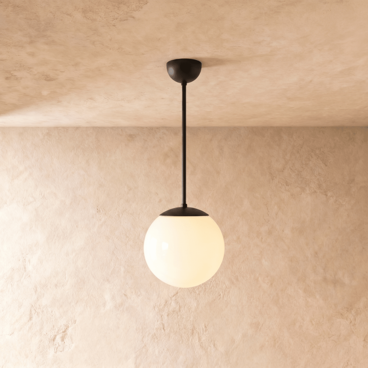 Clérachic globe pendant light in matte black, hung on a rod from a plaster ceiling and photographed in studio.