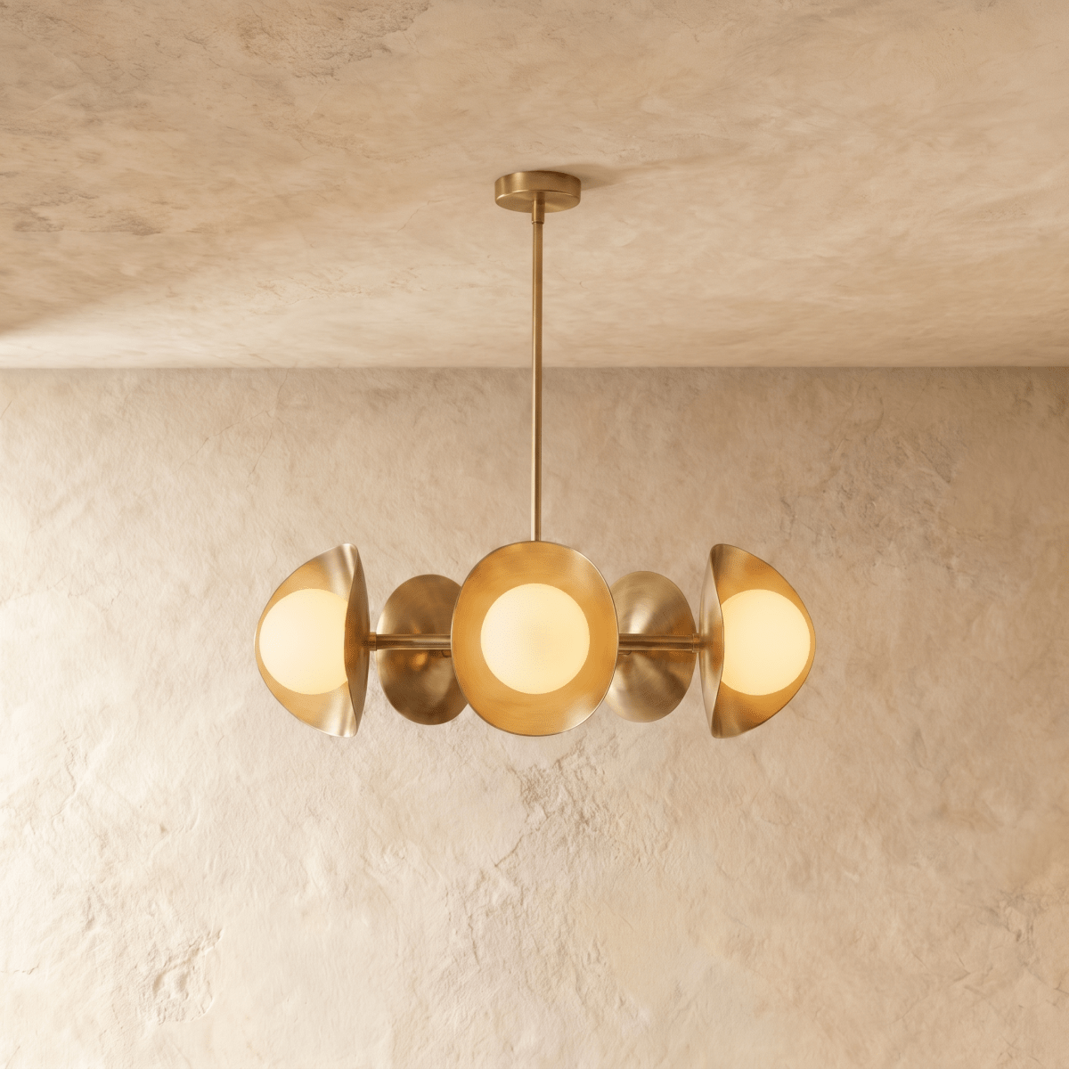 Clérachic chandelier in a brighter brass finish, its row of overlapping discs and opal globes below a ceiling.