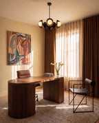 Clérachic matte black chandelier glowing above a walnut desk in a study with a leather chair and framed artwork.