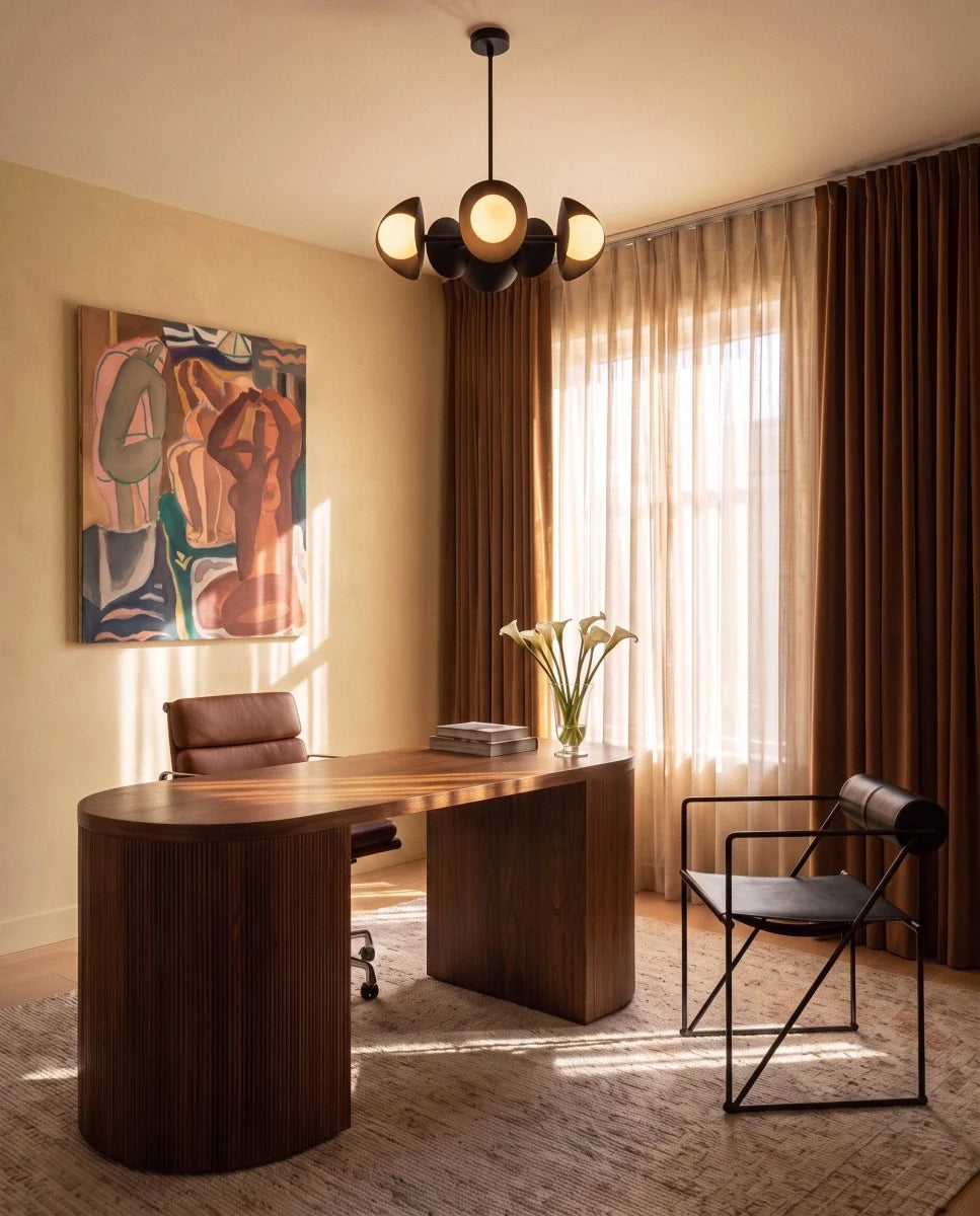 Clérachic matte black chandelier glowing above a walnut desk in a study with a leather chair and framed artwork.