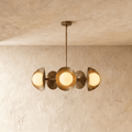 Clérachic chandelier in vintage brass, its row of overlapping discs and opal glass globes below a plaster ceiling.