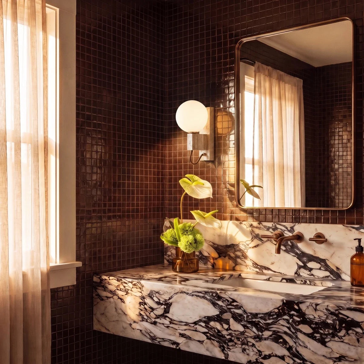 Clérachic wall lamp glowing beside a mirror in a dark tiled bathroom with a marble vanity below.