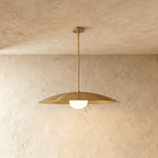 Clérachic pendant light in polished brass, its saucer shade framing an opal glass diffuser beneath.