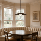 This black Clérachic pendant light hangs above a round table inside a curved upholstered banquette.