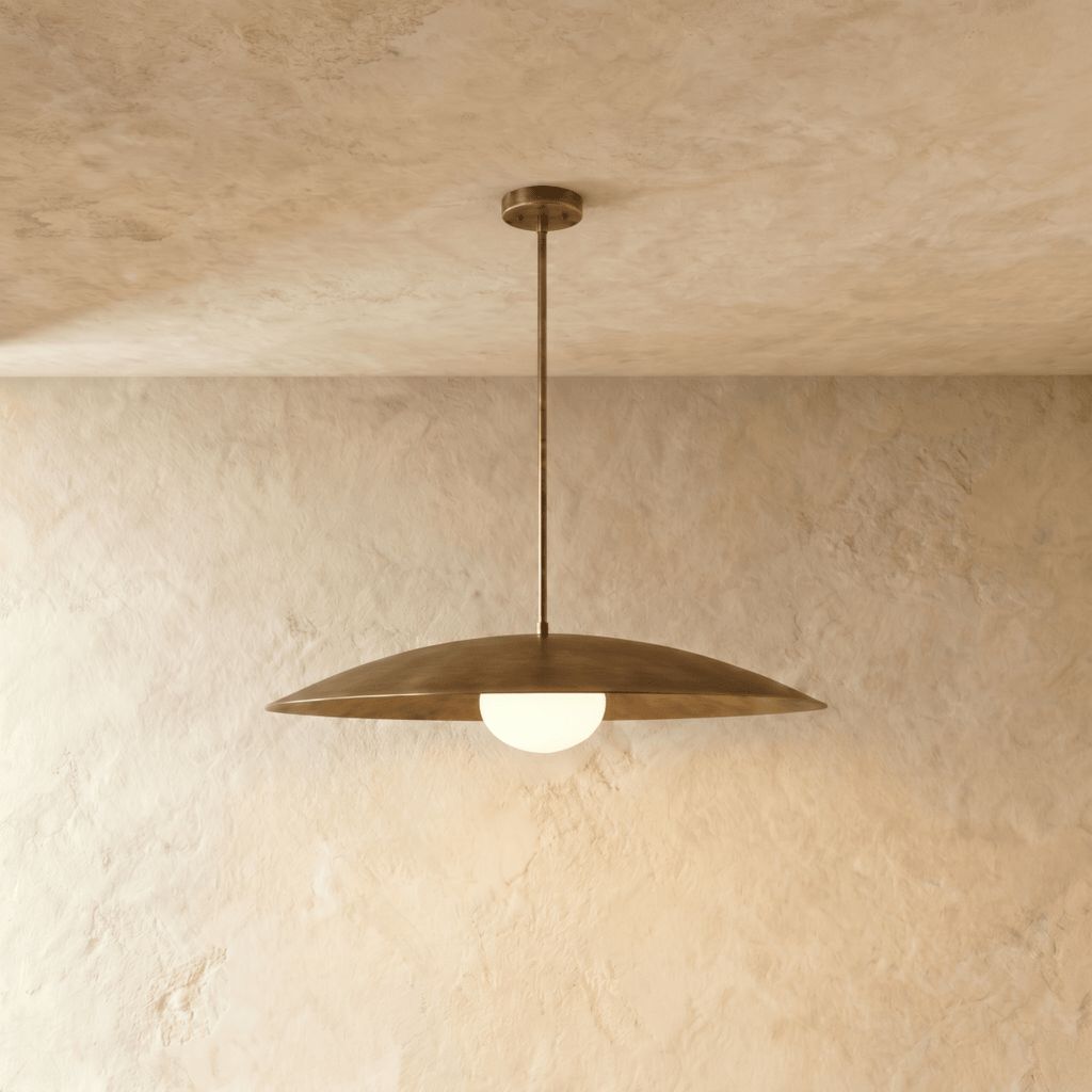 Clérachic pendant light in vintage brass with a wide saucer shade and glowing opal glass diffuser below.