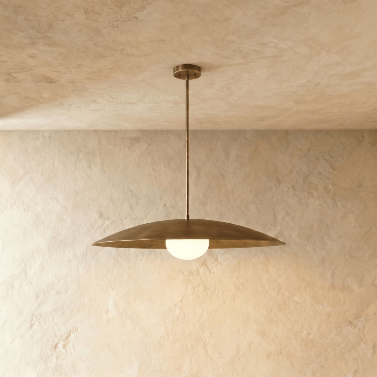 Clérachic pendant light in vintage brass with a wide saucer shade and glowing opal glass diffuser below.