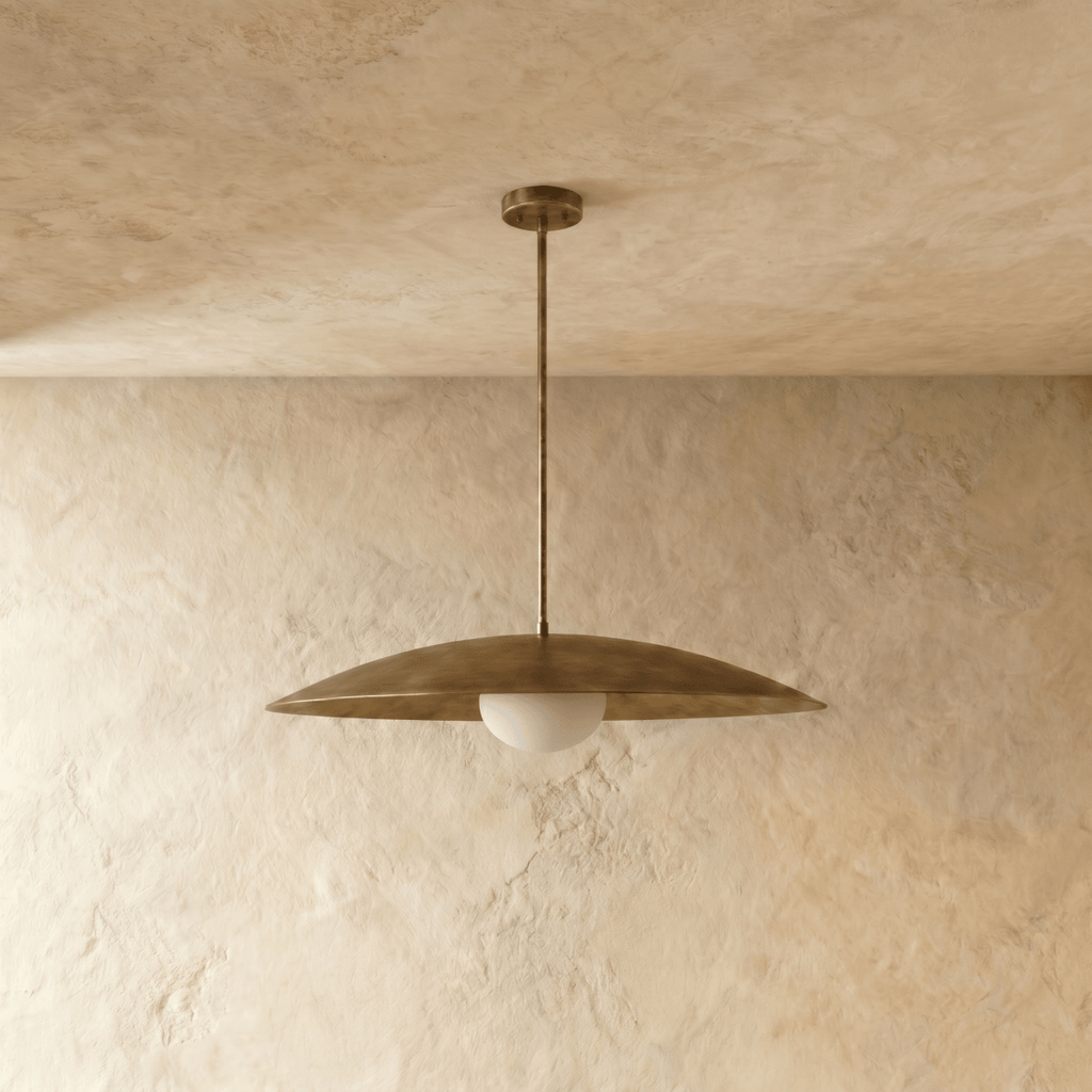This vintage brass Clérachic pendant light is shown from a slightly different angle, its diffuser glowing warm.