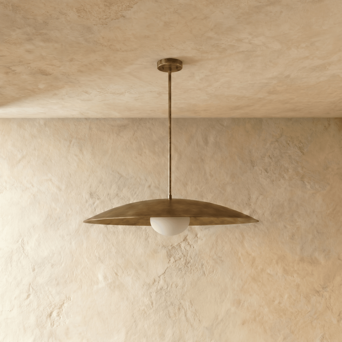 This vintage brass Clérachic pendant light is shown from a slightly different angle, its diffuser glowing warm.