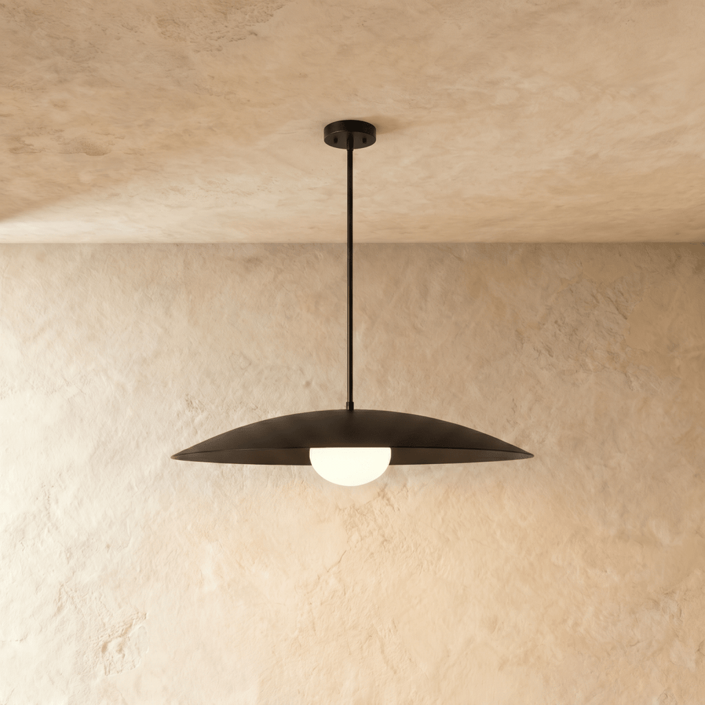 Clérachic pendant light in matte black, its wide saucer shade set above a softly glowing opal diffuser.