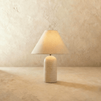 Clérachic Tresa table lamp with a white marble base, lit to show the fine web of hairline veining across the stone.