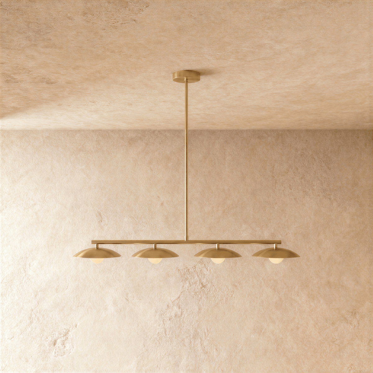 Clérachic bar pendant light in a brass finish, its slim rod dropping from a round ceiling canopy to the horizontal bar that carries four domed shades.