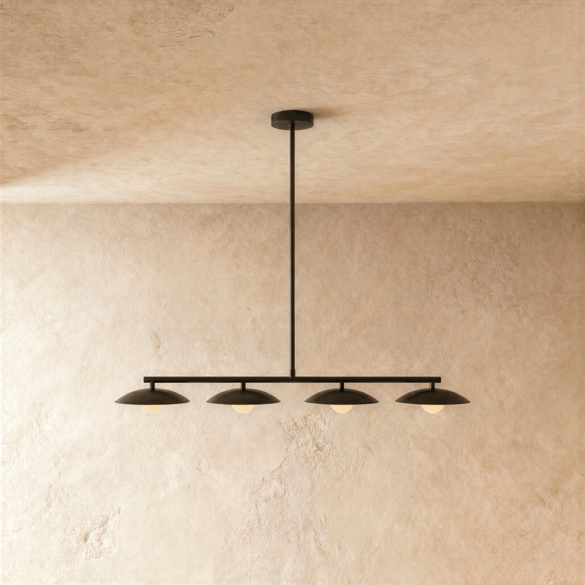 Clérachic linear pendant light in a black finish, four domed shades spaced evenly along the bar with a warm sphere glowing under each.