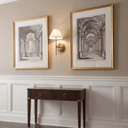 A Clérachic wall light glows between two gilt-framed architectural prints above a dark console table.
