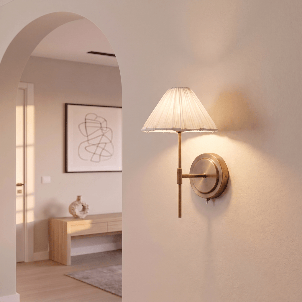 This Clérachic wall light glows softly beside an archway, its pleated shade lighting the plaster wall.