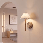This Clérachic wall light glows softly beside an archway, its pleated shade lighting the plaster wall.