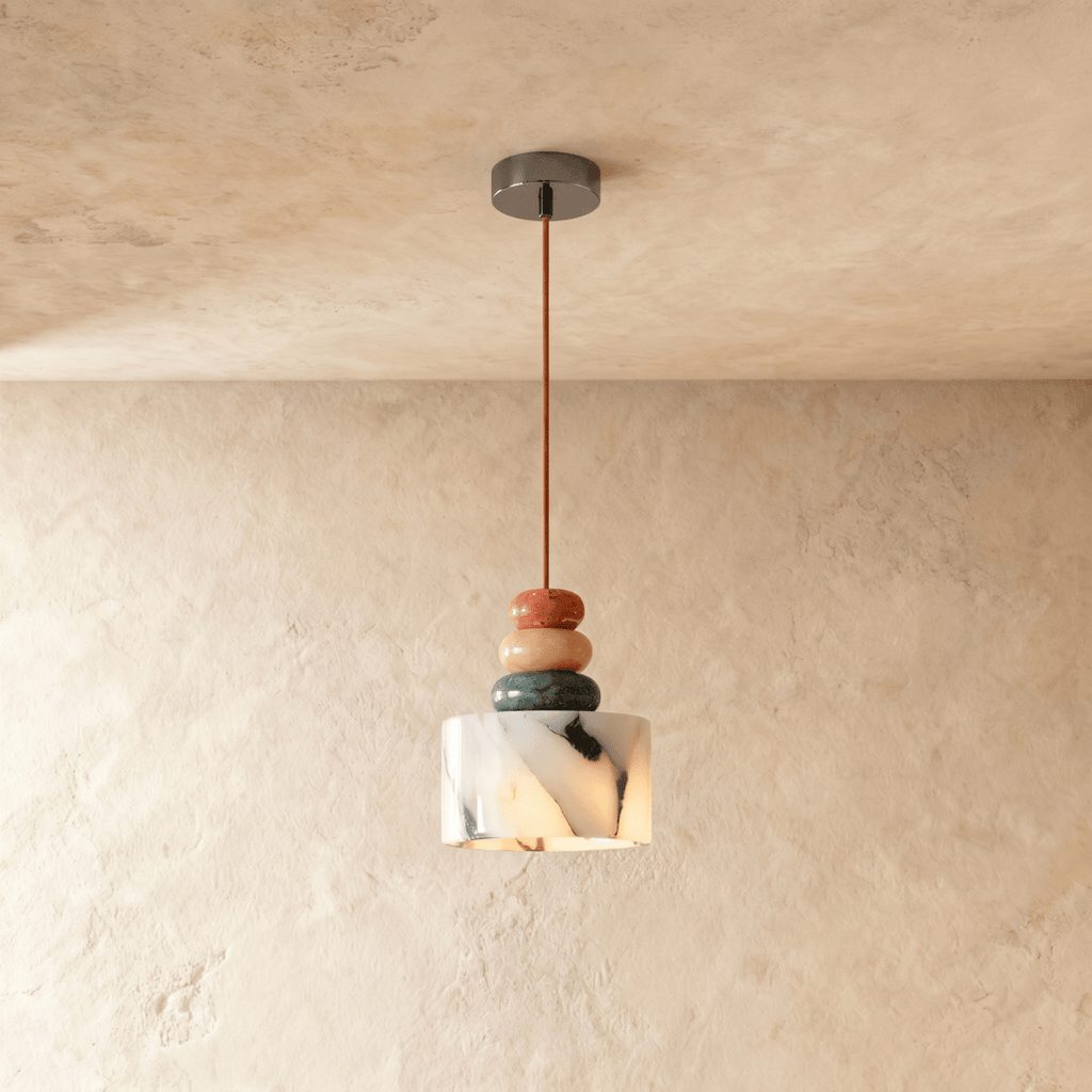 Clérachic stone pendant light hanging from a shallow dark ceiling canopy against a textured plaster wall, its veined shade lit from within below three stacked beads.