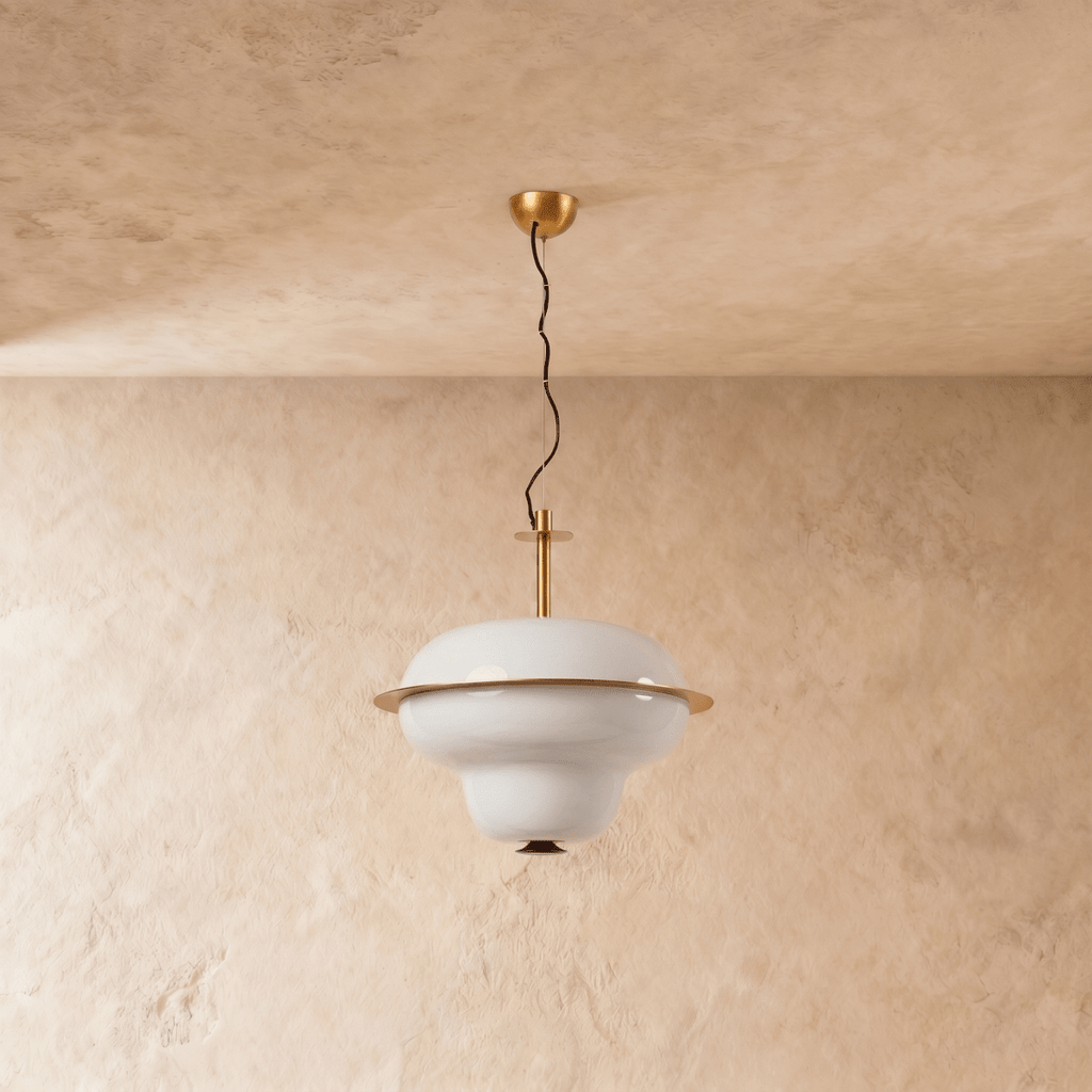 A Clérachic pendant light's tiered opal glass shade catches warm light beneath a brass ceiling mount.
