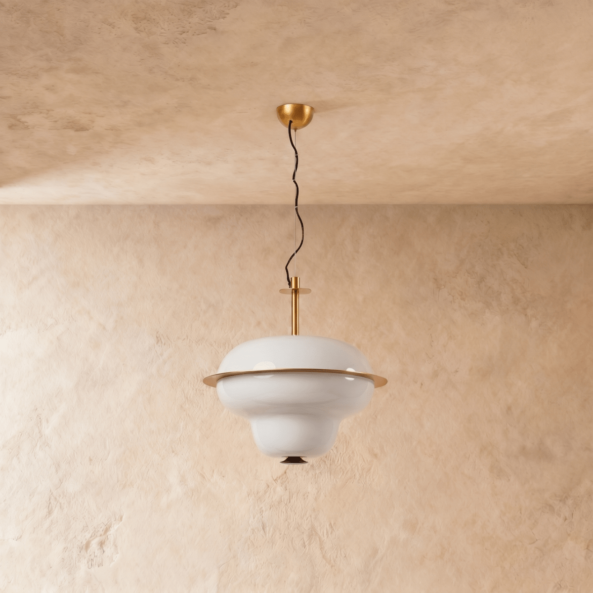 A Clérachic pendant light's tiered opal glass shade catches warm light beneath a brass ceiling mount.