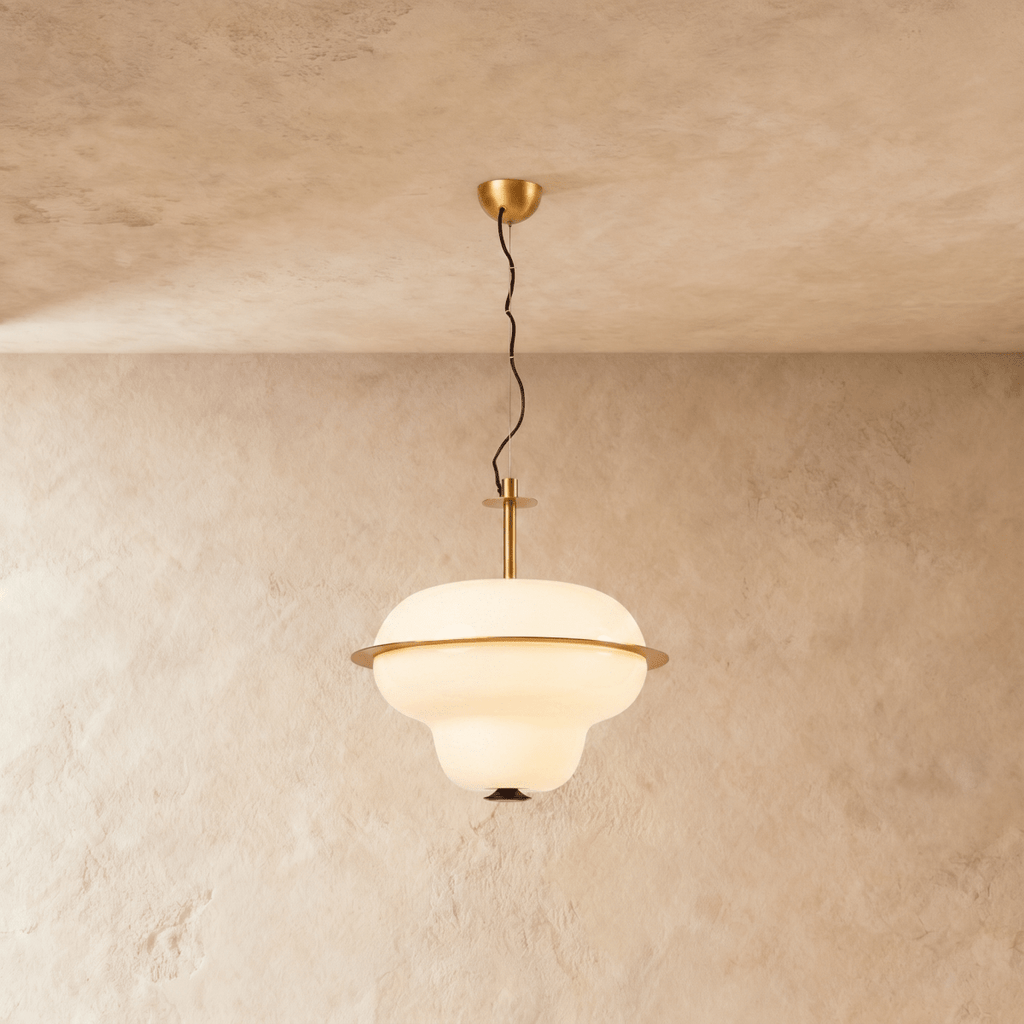 This Clérachic pendant light hangs an opal glass shade with a brass ring band from a plaster ceiling.