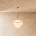This Clérachic pendant light hangs an opal glass shade with a brass ring band from a plaster ceiling.