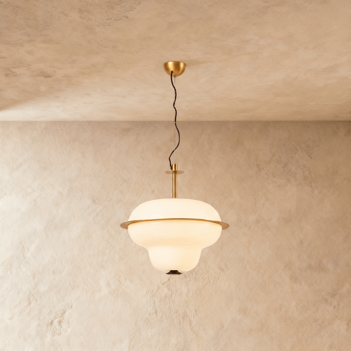 This Clérachic pendant light hangs an opal glass shade with a brass ring band from a plaster ceiling.